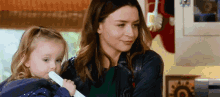 a woman is holding a little girl in her arms while looking at a tablet .