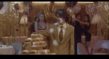 a man in a suit and tie stands in front of a stack of hamburgers .