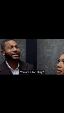 a man in a suit is asking a woman if she is a liar okay