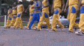 a group of men are walking down a street wearing yellow and blue pants .