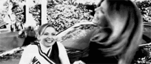 two cheerleaders are standing next to each other in front of a car .
