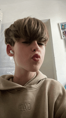 a young boy wearing a tan hoodie with the letters tae on it