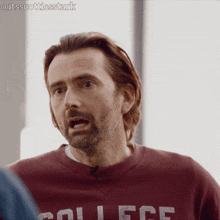 a man wearing a maroon sweater with college on it