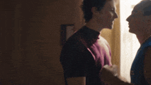 a man in a maroon shirt holds a woman 's arm