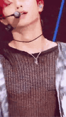 a close up of a man wearing a choker and a microphone on a stage .