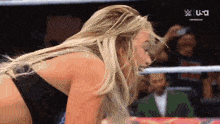 a woman is kneeling down in a wrestling ring while a man takes a picture of her .