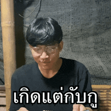 a man wearing glasses and a black shirt has a foreign language sticker on his chest