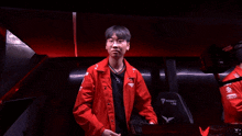 a young man wearing glasses and a red jacket is sitting in a locker room .