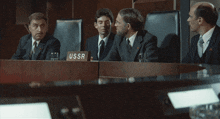 three men sit at a table with a sign that says ussr on it