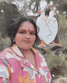 a woman in a pink floral shirt is smiling in front of a statue of a duck