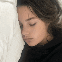 a woman is sleeping with her eyes closed and her head resting on a pillow
