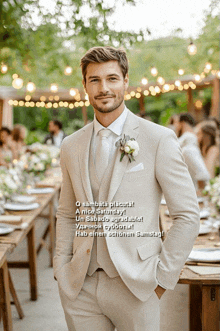 a man in a tan suit stands in front of a table with flowers on it