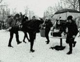 a group of people are dancing in the snow and one of them is holding an umbrella that says coca cola
