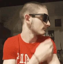a man wearing sunglasses and a red shirt that says ' pin ' on it