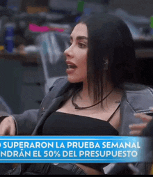 a woman is sitting in front of a banner that says superaron la prueba semanal