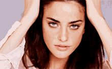 a close up of a woman holding her head with both hands
