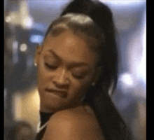 a woman with a ponytail is making a funny face and looking over her shoulder .