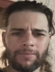 a close up of a man 's face with a beard and long hair .