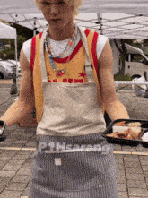 a man in an apron holds a tray of food with the word safety on the apron