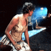 a woman is kneeling down in a dark room with a wooden bucket in front of her