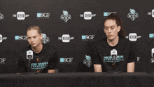 two women wearing new york basketball shirts are sitting at a table with microphones