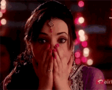 a woman in a purple dress is covering her mouth with her hands