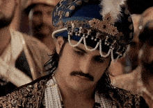 a man wearing a turban and pearls looks down at something