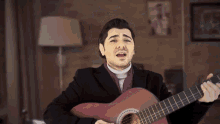 a man is singing while holding a guitar in front of a lamp
