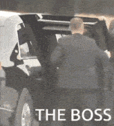 a man in a suit is getting out of a car with the words " the boss " above him