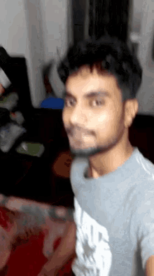 a man with a beard is wearing a grey shirt that says ' a ' on it