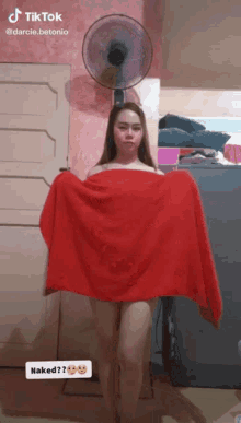 a woman is naked and holding a red towel in front of a fan that says tik tok