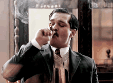 a man in a suit is smoking a cigarette