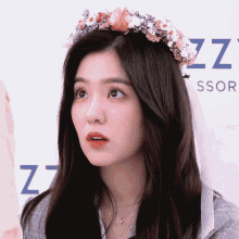 a woman wearing a flower crown stands in front of a sign that says zzz