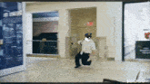 a man in a police uniform is running through a hallway with a sign that says $ dood on it
