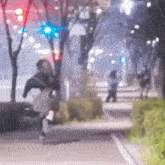 a blurry picture of a person riding a horse down a street at night .