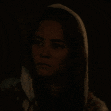 a woman with a hood on her head is looking at something in the dark