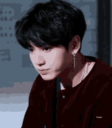 a close up of a person wearing earrings and a red jacket .
