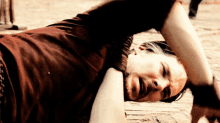 a man in a red shirt is laying on the ground with his arm outstretched