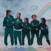 a group of people in green uniforms are standing next to each other in front of a rainbow .