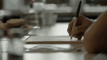 a person writing on a piece of paper with a pencil