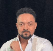 a man with a beard is wearing a white shirt and vest