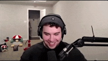 a man is wearing headphones and smiling in front of a microphone .