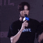 a man in a black t-shirt is holding a microphone and speaking into it .
