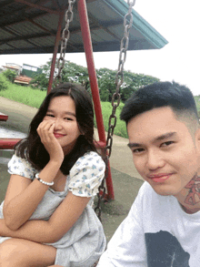 a man and a woman are sitting on a swing