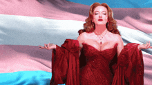 a woman in a red dress stands in front of a pink and blue flag