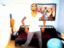 a man is dancing in a living room with a picture on the wall behind him