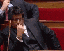 a man in a suit and tie is applauding in a theatre