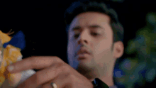 a man with a ring on his finger is holding a piece of food