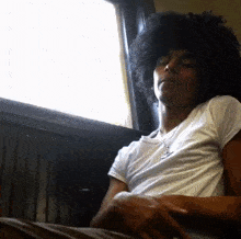 a man with a big afro is sitting in front of a window .