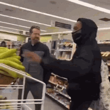 a man wearing a mask is standing next to another man in a store ..